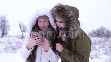 爆笑女孩们在冬天雪花飘落的背景上看小玩意的照片